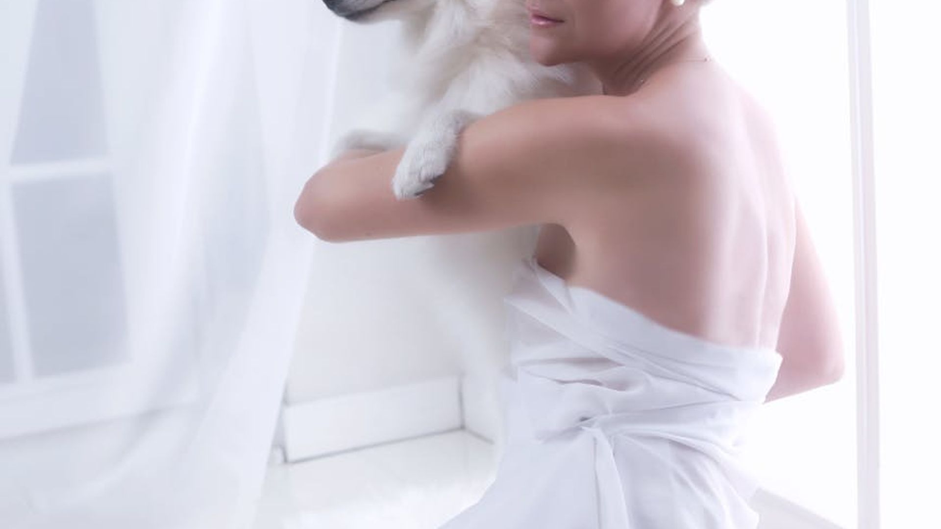Woman meditating in a bright white room with soft sunlight